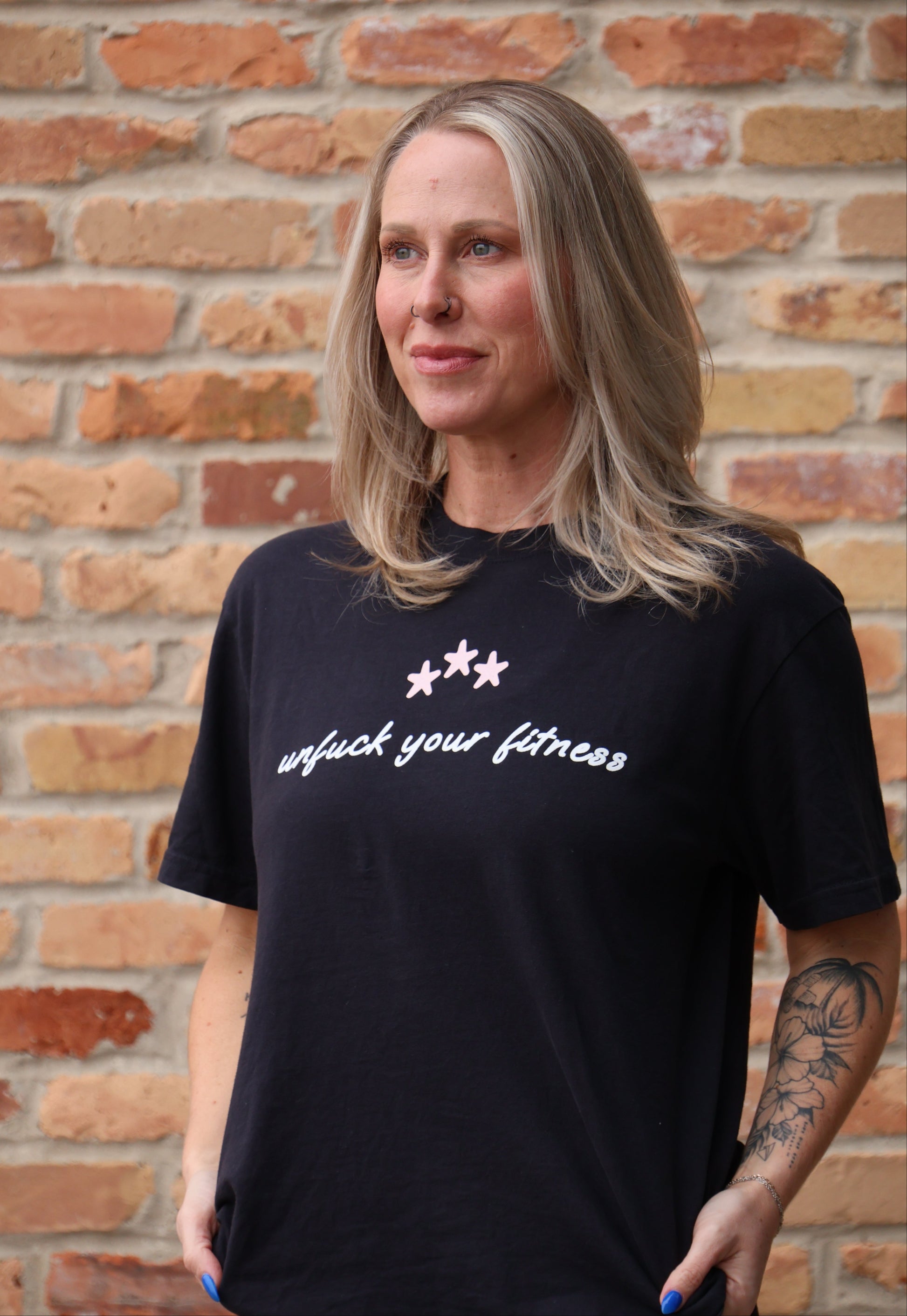 Person wearing a black t-shirt with white text against a brick wall