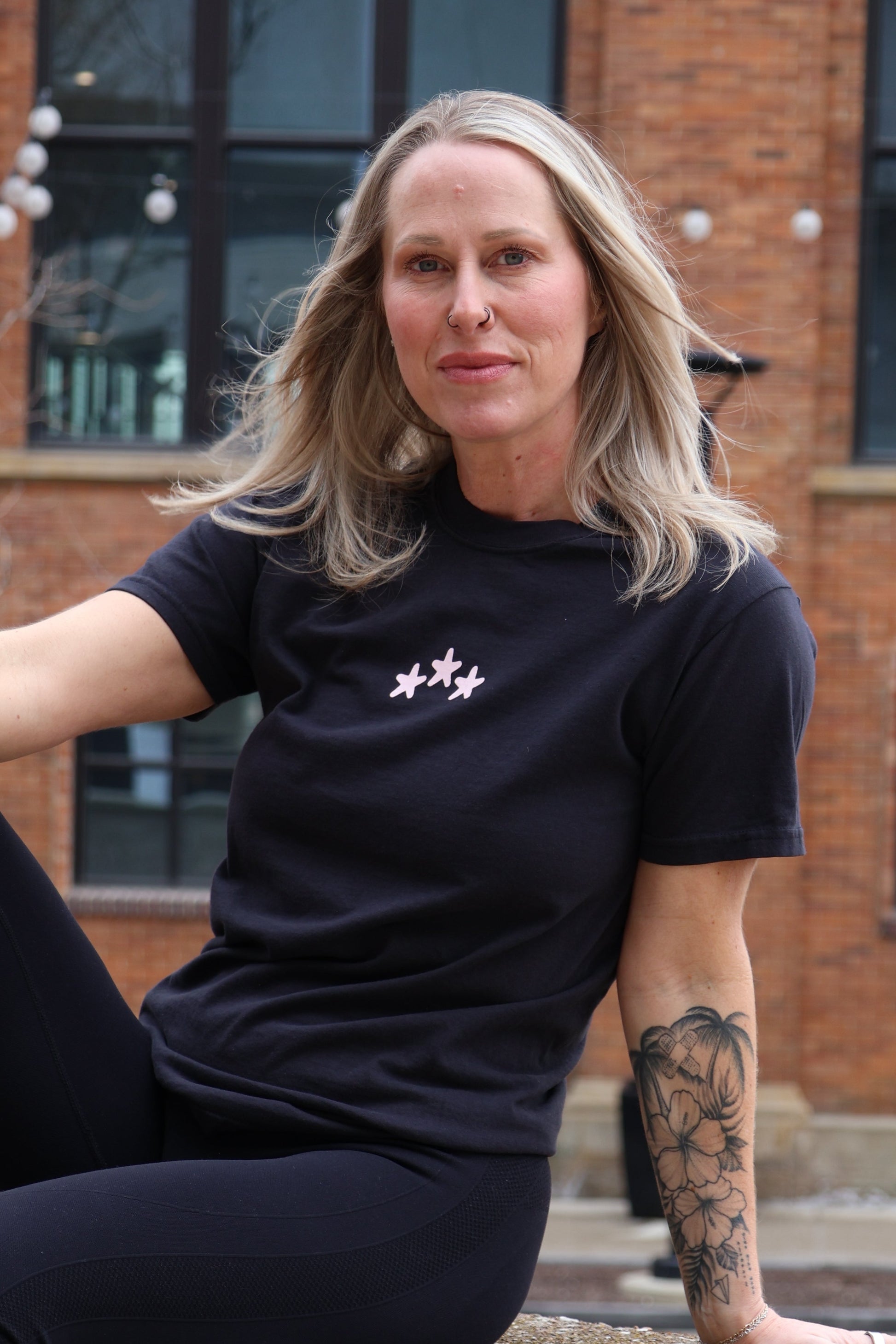 Person in black athletic wear sitting on a stone surface with a building in the background